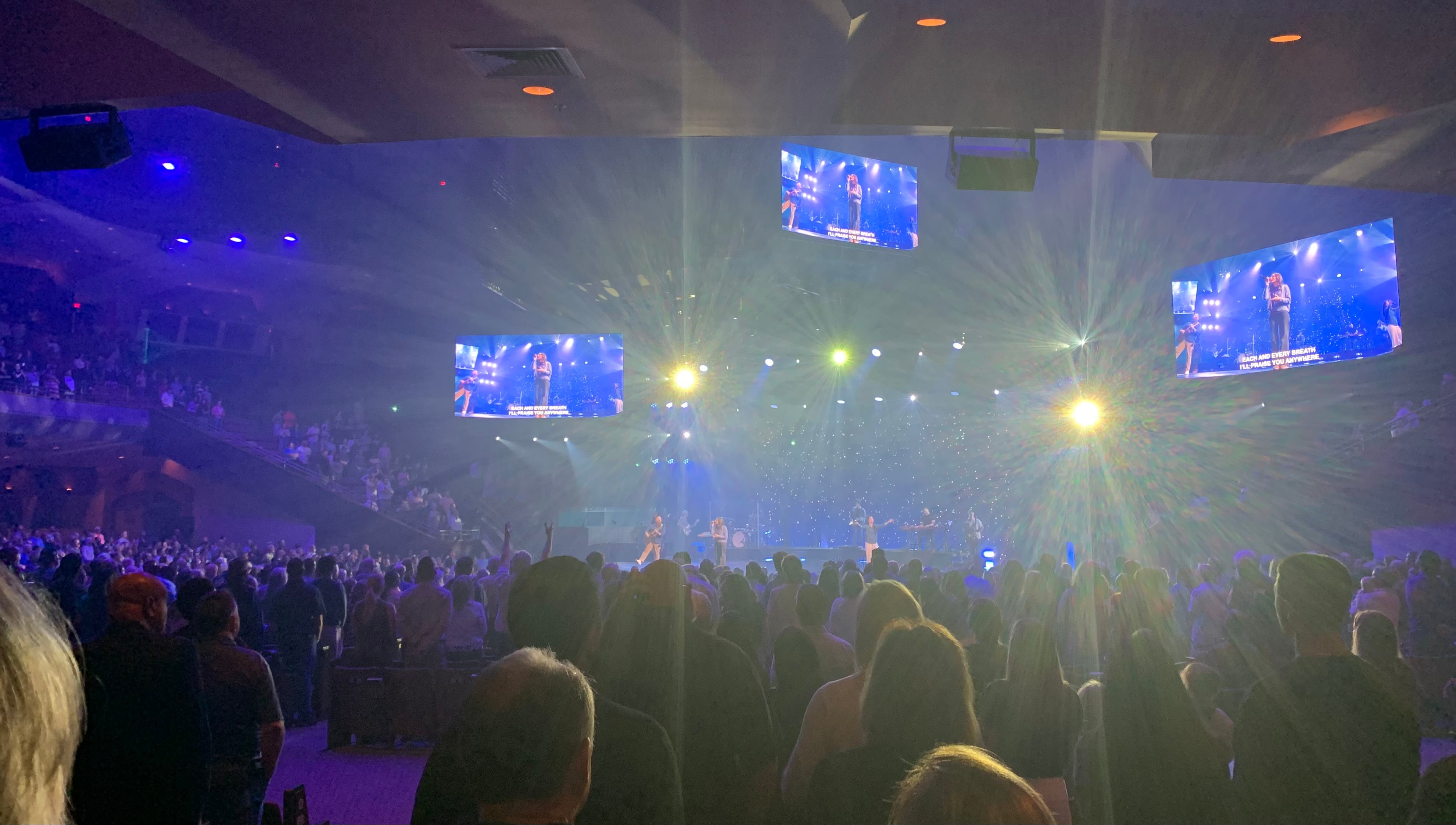 Church worship team using projection screens displaying song lyrics during a live service